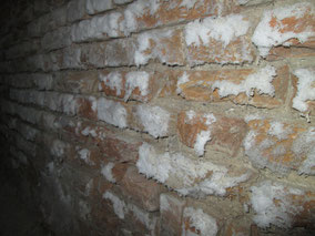 Aantasting door zouten rondom de laaddeuren (boven) en ernstige zoutuitbloei in het pand.