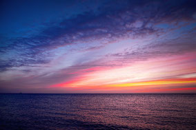 Meer mit Sonnenuntergang violett rosa als Symbolbild für Entsapnnungsverfahren
