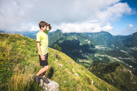 Junge steht stolz auf einem Berggipfel während einer Vater-Sohn-Reise