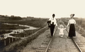 A late 19th century family taking a stroll down a set of railroad tracks