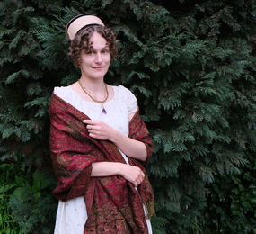 Photo wearing Regency dress in white with shawl and hat in garden