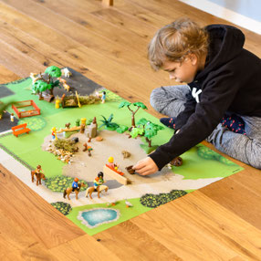 Kind spielt mit Playmobil auf der Spielmatte