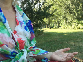 Nahansicht einer Frau, die auf einer Wiese meditiert.  