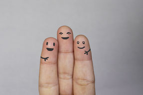 Ein Bild mit drei Fingern auf denen Gesichter gemalt sind und sich umarmen