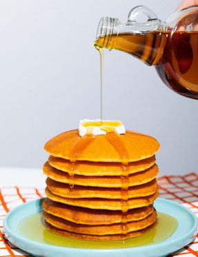 Sirop versé sur une pilée de crêpes dans une assiette 