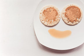 Auf dem Bild ist ein Teller mit zwei Pfannkuchen und Sirub abgebildet. Das ganze ergibt ein Gesicht. Für mehr Informationen, bitte den Bilduntertitel lesen.