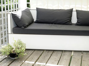Individuell gefertigte Balkon-Lounge aus Vollkernplatten mit wetterfesten Outdoor-Polstern als platzsparende Sitz- und Liegelösung für einen kleinen Balkon.