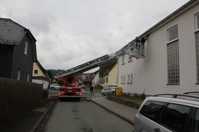 Mit Hilfe einer Drehleiter befestigt die Feuerwehr Schwalbennisthilfen in größerer Höhe am Haus unter einem Dachüberstand.