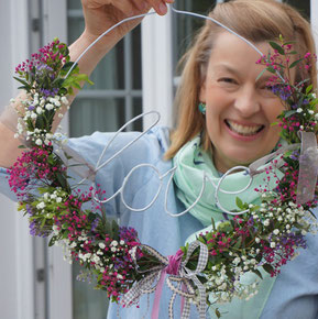 Blumenkranz mit Sommerblumen binden auf einem Kleiderbügel
