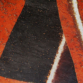 Aus Baumrinde hergestelltes Textil in unterschiedlichen Braun-, Ocker- und Schwarztönen.