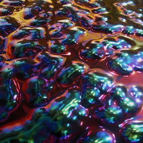 Changierende und spektrale Farbeffekte auf einer Metalloberfläche.