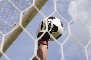 Das Bild zeigt die Hand eines Torwärters, der einen Fussball vor dem Netz fängt: Fokussierung stärken und mentale Blocken überwinden als häufiges Ziel im mentalen Coaching.