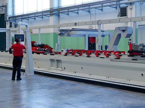 Foto von einer speziell angefertigten Maschine, die mindestens 6 Meter lang ist, vor ihr steht eine Person in rotem T-shirt und schwarzer Hose.