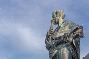 Bronzestatue eines Philosophen mit Schriftrollen – Symbol für Wissen, Nachdenken und den Weg geistiger Klarheit.