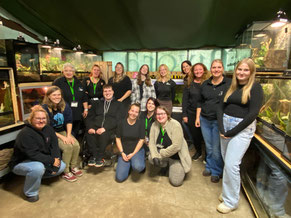 Een groepsfoto van de vrijwilligers van stichting carnivora. Op de achtergrond staat de dierenambulance