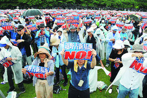 辺野古移設阻止を訴えるプラカードを掲げる大会参加者=11日、奥武山陸上競技場