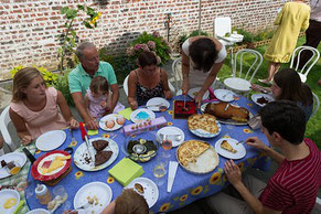 Une famille réunie pour un repas d'anniversaire dehors sur une terrasse dans un jardin