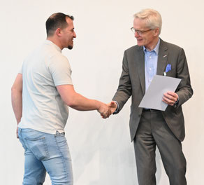 Absolvent erhält das Dokument mit einem Lächeln vom Vereinsobmann