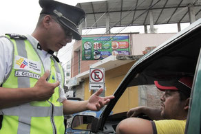 Un agente de tránsito instruye y advierte a un chofer las normas viales. Manta, Ecuador.