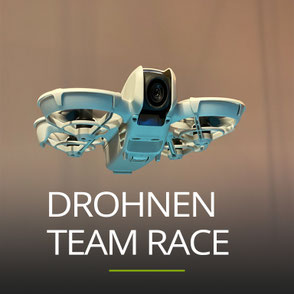 Nahaufnahme von einer Drohne in einem Seminarraum, Schriftzug: DROHNEN TEAM RACE