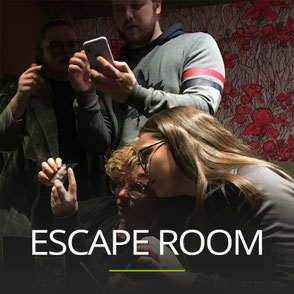 Mehrere Menschen beim gemeinsamen rätseln, Schriftzug: ESCAPE ROOM