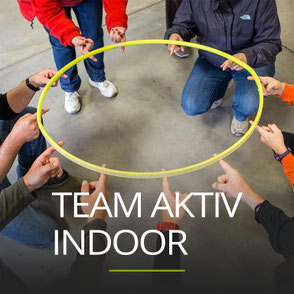 Gruppe hält einen Hula Hoop Reifen, Schriftzug: TEAM AKTIV INDOOR