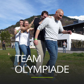 Lachende Menschen bei der Teamübung Riesenski, Schriftzug: Teamolympiade