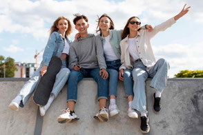 Jugendliche sitzen auf Mauer vor Arztpraxis Gauting.