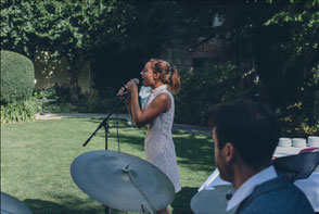 Chanteuse élégante interprétant une chanson française dans un salon de réception à Angers, lumière tamisée et invités attentifs.