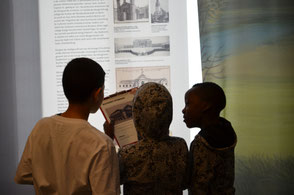Drei Jungen erkunden eine Ausstellung zur Stadtgeschichte.