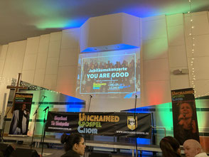 Leere Bühne mit UGC-Banner, Mikrofonen und buntem Licht im Hintergrund