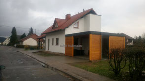 sie sehen ein einfamilienhaus im farbton weiß mit einem carport im farbton kiefer