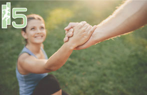 Einer sportlichen Frau, die am Boden liegt, wird aufgeholfen
