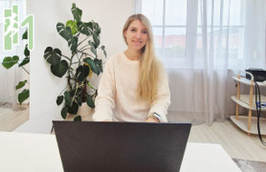 Julia Emberger sitzt vor dem Laptop und lächelt