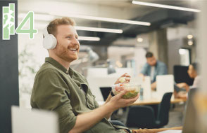 Ein Mann mittleren Alters isst Salat bei der Arbeit und lächelt