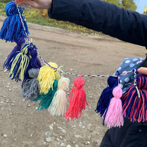Bommel‑Party: Kinder gestalten bunte Ketten inmitten der Alpaka‑ und Lamaherde.