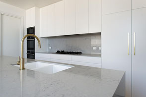 Ocean View kitchen – minimalist design with brass tapware and stone benchtops