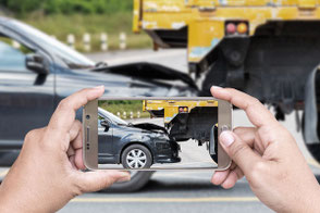Eine Fotoaufnahme mit Smartphone von einem beschädigten Fahrzeug.