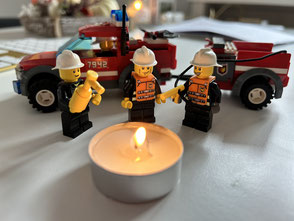 Lego-Feuerwehrmänner um brennendes Teelicht
