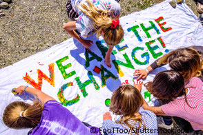 Jugendliche malen Transpartent, darauf steht "we are the change" Hoffnung für bessere Zukunft und Klimaschutz