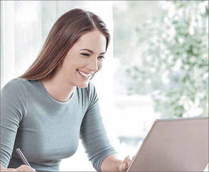 Frau lächelt bei der Arbeit am Laptop - Online Seminare und Mediathek von meta Fackler