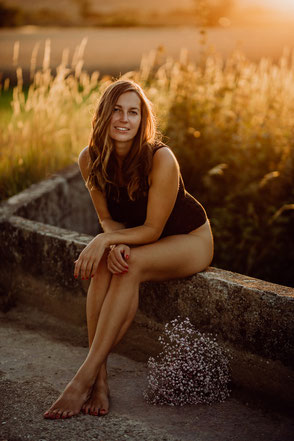 Portrait einer jungen Frau, die im Sonnenuntergang bei Mainz auf einer Mauer sitzt