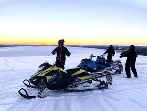 Zwei Schneemobile auf dem Hügel im Sonnenuntergang