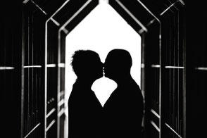 Silhouettenfoto in Schwarz-Weiß: ein Pärchen küsst sich im Gegenlicht.