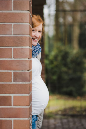 babybauch-schaut-hinter-mauer-hervor-schwangerschaft-babybauchfotos-draussen-duesseldorf-duisburg