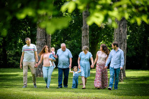 Glückliche Familie mit Großeltern und Enkelinnen geht gemeinsam Hand in Hand im Park.