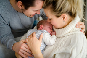 Glückliche Eltern halten liebevoll ihr schlafendes neugeborenes Baby im Arm.
