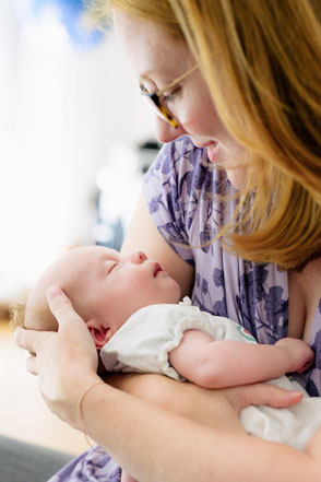 Inniger Moment: Mutter hält ihr schlafendes neugeborenes Baby liebevoll im Arm.