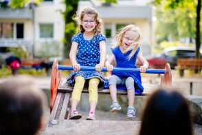 Gewschwister haben viel Spaß beim Wippen auf dem Spielplatz.