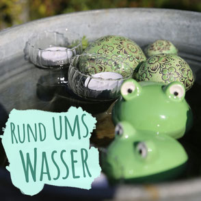 Wasserpumpe in Form eines gusseisernen Froschkönigs mit goldener Krone auf einer Kugel. Bild trägt die Aufschrift "Rund ums Wasser".